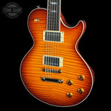 A classic electric guitar with a vibrant sunburst flame finish, featuring gold hardware and a dark fretboard, shown against a solid black background with a Tone Shop watermark in the top left corner.