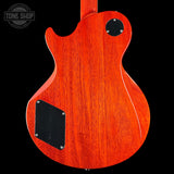 The back of an electric guitar with a vibrant orange-red cherry finish, featuring a black pickguard and circular control plate, shown against a black background with a Tone Shop watermark.
