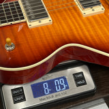 Close-up of a guitar body resting on a digital scale to show its weight, with the scale displaying 8.9 lbs.