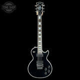 A black Gibson Les Paul Custom electric guitar with white binding and white block inlays, shown vertically against a solid black background. A 'TONE SHOP' watermark is visible in the top-left corner.
