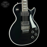 A black electric guitar with white trim, featuring a glossy finish, chrome hardware, and a dark fretboard, shown against a solid black background with a Tone Shop watermark in the top left corner.