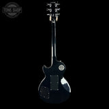 A black electric guitar shown from the back against a solid black background, featuring a glossy finish, chrome tuning pegs, and a Tone Shop logo in the upper left corner.