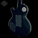 The rear view of a glossy black electric guitar against a solid black background, featuring a silver circular badge and two black pickguard covers.