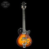 A classic electric guitar with a sunburst finish, featuring a black pickguard, chrome hardware, and a silver tremolo tailpiece, shown against a solid black background with a Tone Shop watermark in the top left corner.