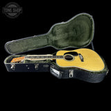 Acoustic guitar in a hard-shell case with 'Tone Shop' logo.