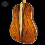 Close-up of a wooden acoustic guitar back with 'Tone Shop' logo.