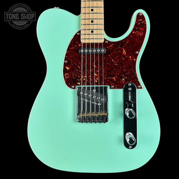 Electric guitar with a turquoise body and red pickguard on a black background