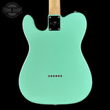 Turquoise electric guitar body with a visible brand logo on a black background