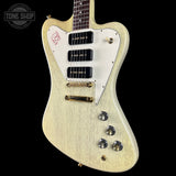Electric guitar with a white pickguard and gold hardware on a black background, featuring the Tone Shop logo.