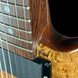 Close-up of a guitar's neck and body with a focus on the wood grain and strings.