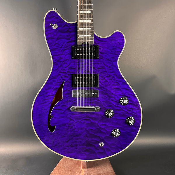 Purple electric guitar with a wavy finish on a gray background