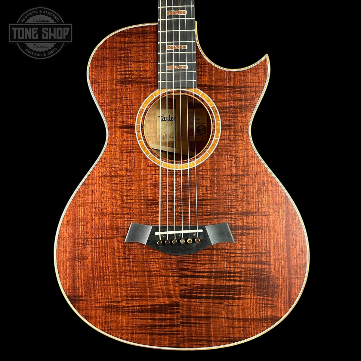 Acoustic guitar with a dark wood finish on a black background, featuring the Taylor brand.