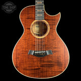 Acoustic guitar with a dark wood finish on a black background, featuring the Taylor brand.
