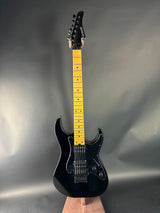 Black electric guitar with a yellow fretboard on a gray background