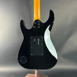 Black electric guitar with a wooden neck on a gray background
