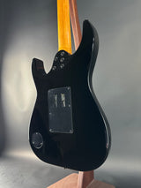 Black electric guitar body on a gray surface