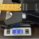 Black electric guitar on a digital scale displaying weight