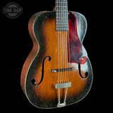Vintage acoustic guitar with a dark brown finish on a black background, featuring the Tone Shop logo.