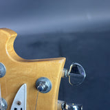Close-up of a guitar's headstock with tuning pegs against a dark background