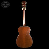 Back view of a wooden acoustic guitar on a black background with 'Tone Shop' logo.