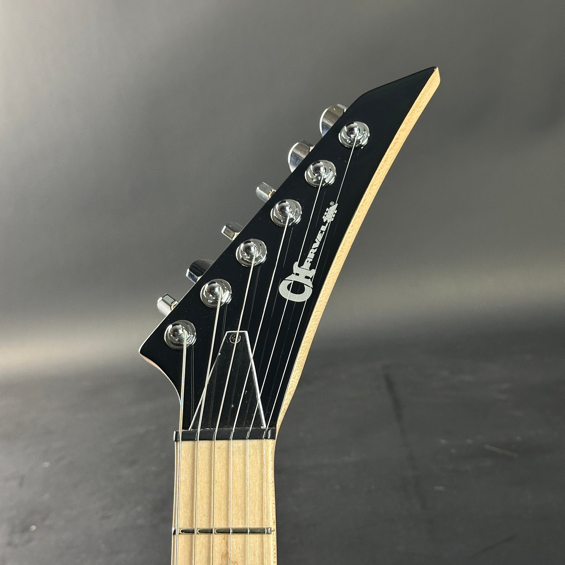 Guitar headstock with brand logo on a gray background