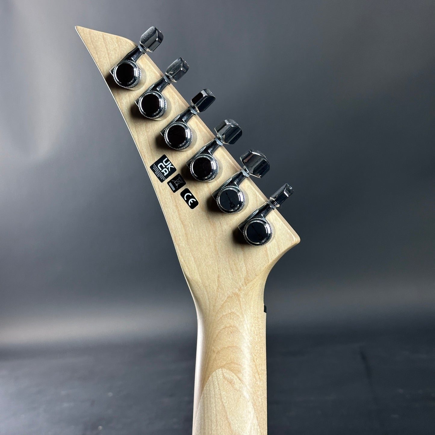 Close-up of a guitar headstock with tuning pegs on a dark background
