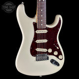 White electric guitar with a dark red pickguard on a black background, featuring the Tone Shop logo.