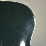 Close-up of a glossy black guitar body showing the edge contour and visible surface scratches against a neutral gray background.