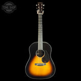 Acoustic guitar with a sunburst finish on a black background, featuring the Tone Shop logo.