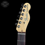 Close-up of a Fender Telecaster electric guitar headstock and upper neck against a black background, with six black tuning pegs and the Fender Telecaster logo visible.