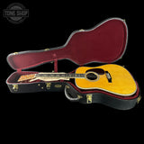 Acoustic guitar in a hard-shell case with 'Tone Shop' logo.