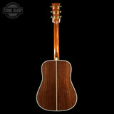 Back view of a wooden acoustic guitar with 'Tone Shop' logo in the corner.