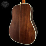 Back view of a wooden acoustic guitar with 'Tone Shop' logo in the corner.