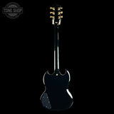 A black electric guitar shown from the back against a solid black background, with gold tuning pegs and a Tone Shop watermark in the top left corner.