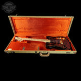 A black electric guitar with red flame-style body graphics, displayed inside an open vintage-style hard case lined with bright orange velvet. The case is photographed against a solid black background, with a Tone Shop watermark in the upper left corner.