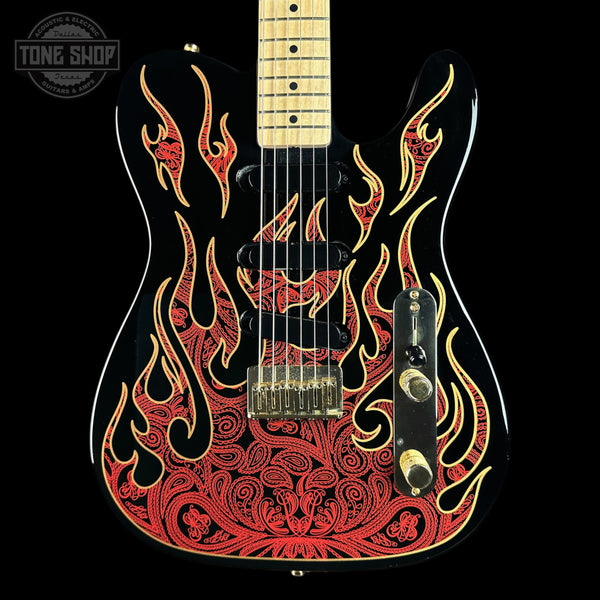 A black electric guitar with a red and gold flame pattern on the body, featuring a maple neck and gold hardware, shown against a black background with a Tone Shop watermark in the top left corner.