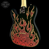 A custom black electric guitar body featuring intricate red and gold flame and scroll patterns, shown against a solid black background with a Tone Shop watermark.