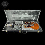 Brown guitar in a hard-shell case with 'Tone Shop' logo.