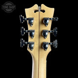 Close-up of a guitar headstock with tuning pegs on a black background, featuring the Tone Shop logo.