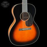 A classic acoustic guitar with a sunburst finish, featuring a dark black outer edge fading to a vibrant orange and brown center, set against a solid black background.