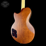 Wooden guitar body with a black pickguard on a black background, featuring 'Tone Shop' branding.