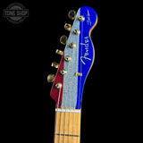 Close-up of a Fender Stratocaster electric guitar headstock featuring a blue and red split design with a silver glitter maple neck, set against a solid black background.