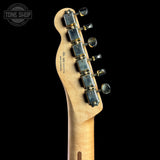 Close-up of the headstock of a Fender Stratocaster electric guitar in natural maple wood, featuring six silver tuning pegs with black knobs and gold-toned springs, set against a solid black background.