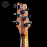 Close-up of the headstock of a wooden acoustic guitar against a solid black background, showing the six tuning pegs and wood grain.