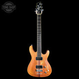 A natural wood single-cutaway electric guitar with black hardware, shown from the front against a solid black background. A Tone Shop watermark is visible in the top-left corner.