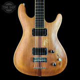 An electric guitar with a natural brown wood finish and black hardware, shown against a solid black background with a Tone Shop watermark in the top left corner.
