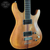 A 6-string electric guitar with a natural wood finish, shown against a solid black background. The guitar features a contoured body, black hardware, and a chrome bridge.