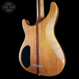 The back of an electric guitar made of glossy, warm brown wood with a dark center stripe and a black pickguard, shown against a solid black background with a Tone Shop watermark in the top left.