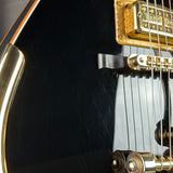Close-up of a black electric guitar with gold hardware
