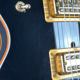 Close-up of a black electric guitar with gold hardware
